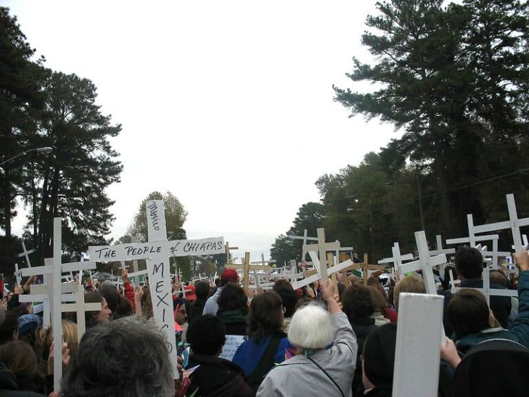 Group of people from behind, all of them are holding white wooden crosses