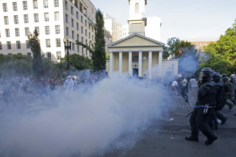 Photo of police and a cloud of what looks like smoke. You can also see protestors in the back.