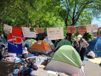 A student encampment on Georgetown's campus with several tents and a clothesline with protest signs hanging from it.